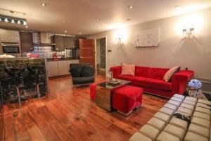 a living room with a red couch and a kitchen at The London Nest: 2BR City Haven in London