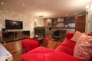 a living room with a red couch and a tv at The London Nest: 2BR City Haven in London