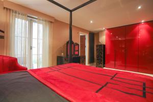 a red bedroom with a large bed with a red blanket at The London Nest: 2BR City Haven in London