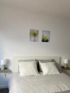 a white bed with two pillows and two paintings on the wall at SeaView Ericeira in Ericeira
