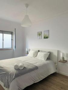 a white bedroom with a large bed with two towels on it at SeaView Ericeira in Ericeira