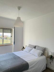 a white bedroom with a bed and a window at SeaView Ericeira in Ericeira