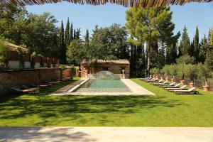 a swimming pool in a garden with chairs and a fountain at Chambre d'h&ocirc;tes Chez Samuel Bruno in Lorgues