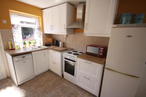 uma cozinha com armários brancos e um frigorífico branco em Moy Fishermans retreat Foxford em Foxford