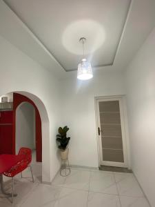 Habitación blanca con silla roja y puerta en Villa Maria & Nour en Awlād ‘Umar