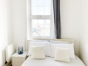 a bedroom with a bed with white pillows and a window at 1 Bedroom City Gem, Prime Location. in Woolwich
