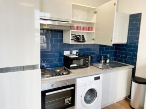 a kitchen with a washer and a sink and a microwave at 1 Bedroom City Gem, Prime Location. in Woolwich