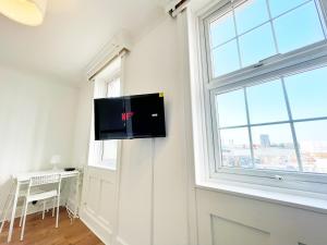 a flat screen tv on the wall of a room with a window at 1 Bedroom City Gem, Prime Location. in Woolwich
