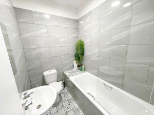 a bathroom with a white tub and a toilet and a sink at 1 Bedroom City Gem, Prime Location. in Woolwich