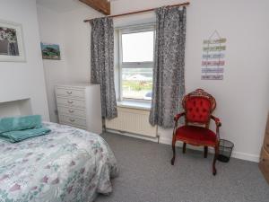 a bedroom with a bed and a chair and a window at 23 Beach Road in Y Felinheli