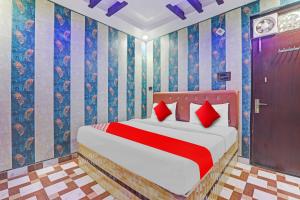 a bedroom with a bed with red pillows and a door at OYO Flagship Ganga Galaxy Hotels And Banquet in Kānpur