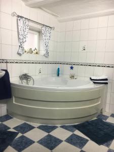 a green bath tub in a white tiled bathroom at Ferienwohnung "Haaler Au" 