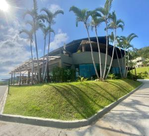 a building with palm trees in front of it at Hotel Caieiras in Guaratuba