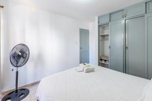 een witte slaapkamer met een bed en een ventilator bij Departamento familiar en Nueva Cordoba by lofty in Cordoba