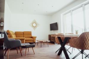 a living room with a couch and a table and chairs at Fitromax Apartmanház in Ajka