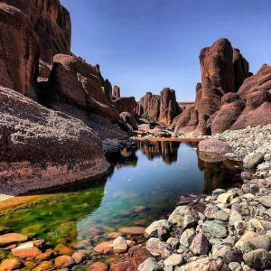 a pool of water in a canyon with rocks at auberge le SIRWA SALAM in Ouarzazate