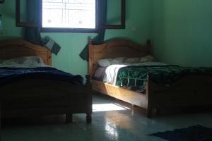 two beds in a room with a window at auberge le SIRWA SALAM in Ouarzazate