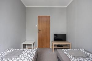sypialnia z dwoma łóżkami, telewizorem i drzwiami w obiekcie Pokoje Wasilkowskiego w Warszawie