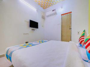 a white bedroom with a bed and a tv at Flagship Le Pondy Paradise in Puducherry