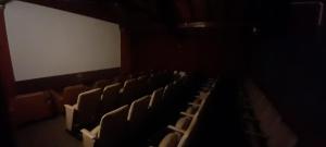 an empty auditorium with chairs and a white screen at Hotel de Cine Las Golondrinas in Villa Gesell
