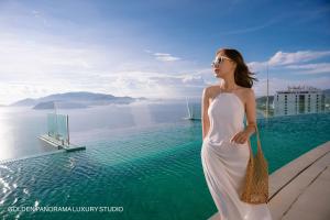 a woman in a white dress standing next to a swimming pool at GOLDEN PANORAMA LUXURY STUDIO in Nha Trang
