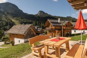 einen Holztisch und Stühle auf einer Terrasse mit Gebäuden in der Unterkunft AlpenParks Hagan Lodge Altaussee in Altaussee