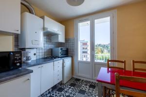 a kitchen with white cabinets and a table and a window at Le Gabadri in Annecy