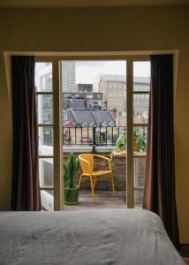 Stylish 1 bedroom in Covent Garden with terrace في لندن: غرفة نوم مع نافذة مع كرسي أصفر على شرفة