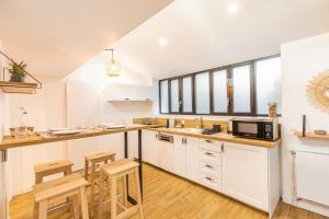 una cucina con armadi bianchi e sgabelli in legno di Peaceful love nest of 40 m in Gentilly a Gentilly
