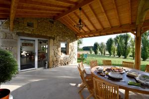 un patio avec une table et des chaises sous un toit en bois dans l'établissement Le Gîte du Taureau, à Sainte-Gemme