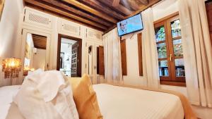 a bedroom with a bed and a tv on the wall at Entre Dos Aguas Hotel Boutique in Toledo