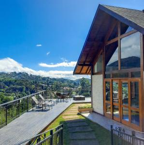 a house with a deck with a table and chairs at Chalés Mirante Monte Verde in Monte Verde