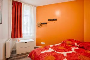 ein Schlafzimmer mit orangefarbenen Wänden und ein Bett mit einer Blumendecke in der Unterkunft Le Havre - Quartier des Docks au Calme - 4 Appartements Entièrement Rénovés - NOUVEAU in Le Havre