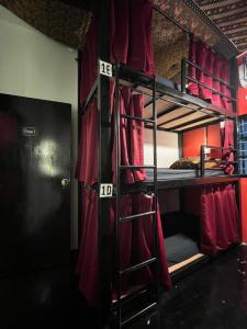 um quarto com 2 beliches e cortinas vermelhas em House of Lion Hostel em Pantai Cenang