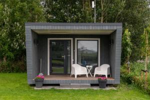 a small shed with two chairs and a table in it at Tiny house aan het water op de appelhof in Wommels +8 photos