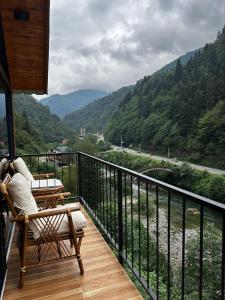 a person sitting in a chair on a balcony overlooking a river at HiraBungalov in Çamlıhemşin
