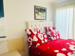 Un dormitorio con una cama roja con almohadas rojas y blancas en Husein Accommodations en Ciudad del Cabo