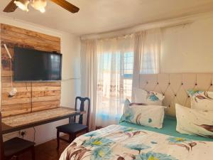 1 dormitorio con 1 cama y escritorio con TV en Husein Accommodations en Ciudad del Cabo