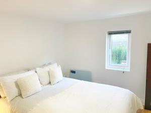 a white bed with white pillows and a window at Prime Woolwich 2 Bed Gem in Woolwich