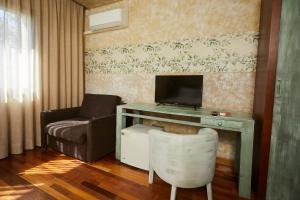 a living room with a desk with a tv and a chair at Hotel El Mirlo Blanco in Candeleda