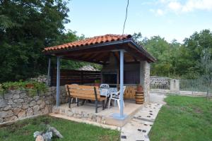 um gazebo com uma mesa e um banco em Apartments Cindric em Malinska