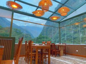 une salle à manger avec une table, des chaises et une grande fenêtre dans l'établissement Hotel Qoya Palace - Machupicchu, à Machu Picchu