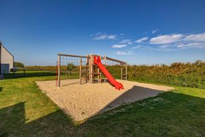 un parque infantil con un tobogán rojo en el césped en Korn-Koje en Büsum