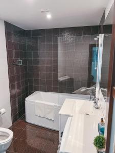 ein Badezimmer mit einer Badewanne, einem Waschbecken und einem WC in der Unterkunft UP 34 FLOOR APARTMENTS in Klaipėda