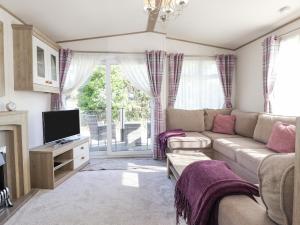 ein Wohnzimmer mit einem Sofa und einem TV in der Unterkunft 29 Lakes View in Carnforth