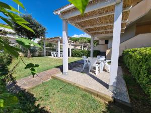 a patio with white tables and chairs under a pergola at Villaggio Mietta in Castiglioncello