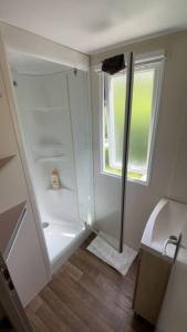 baño blanco con ducha y lavamanos en Chaleureux Mobil Home, en Ivry-la-Bataille