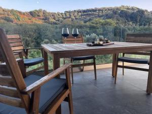 a wooden table with two wine glasses and two chairs at Ek Ornelakis, Luxury Country House with Jacuzzi in Chania Town