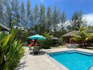 a swimming pool with a table and an umbrella at Casa Tanjung Jara in Dungun