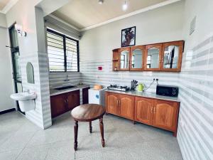 een keuken met houten kasten en een houten kruk bij Success Apartment - Diamond in Mwanza